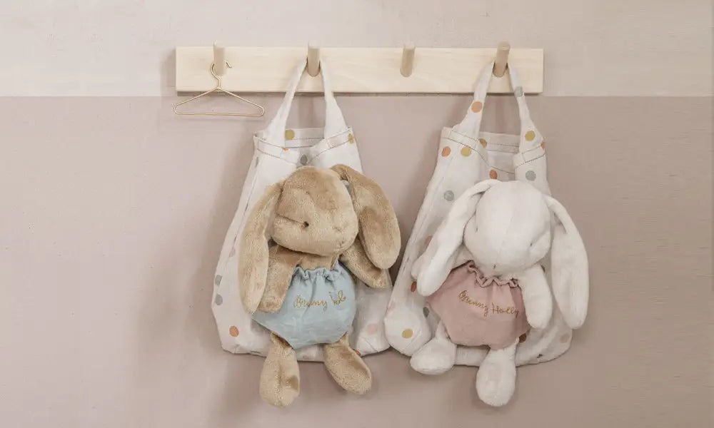 maileg bunnies in a bag hanging on a coat peg