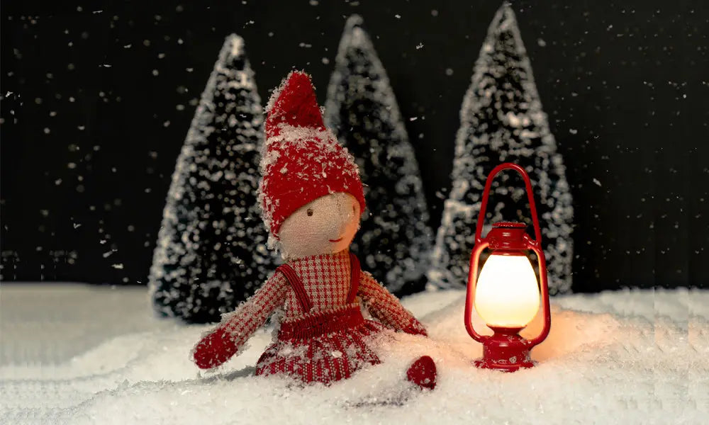 maileg elfie sitting in the snow in the dark with a lantern