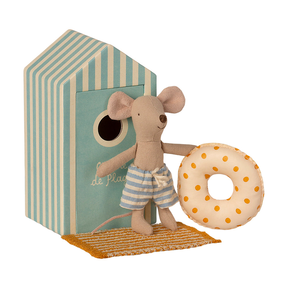 maileg little brother mouse in blue stripe shorts shorts holdiing a rubber ring standing on his yellow towel in front of his blue stripe beach hut box