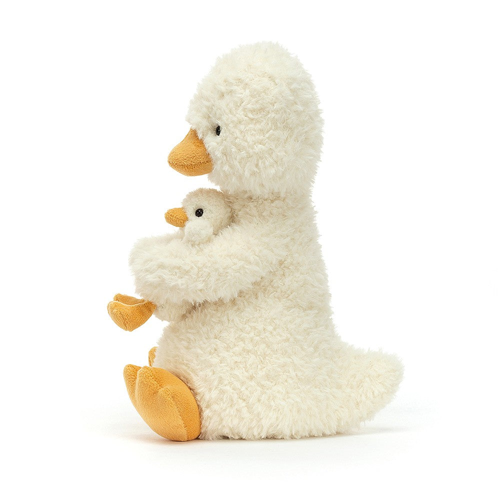 Side view of jellycat pale yellow duck cuddling her little duckling in her arms
