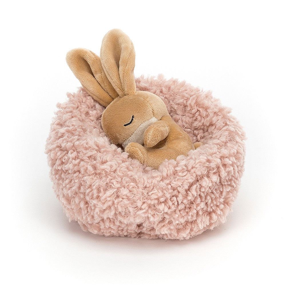 jellycat little bunny curled up asleep in a little blush pink cushion bed